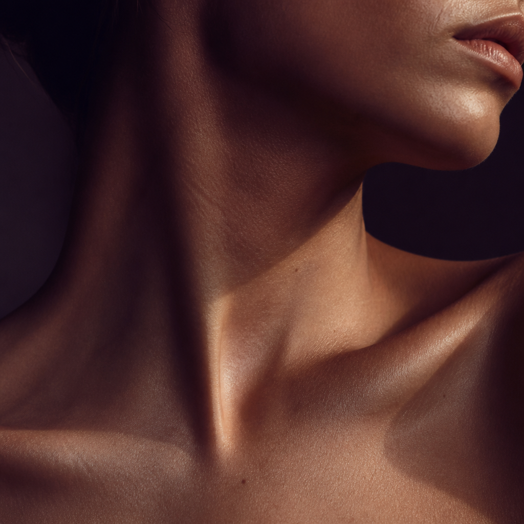 Editorial close-up of a collarbone and neck in warm light